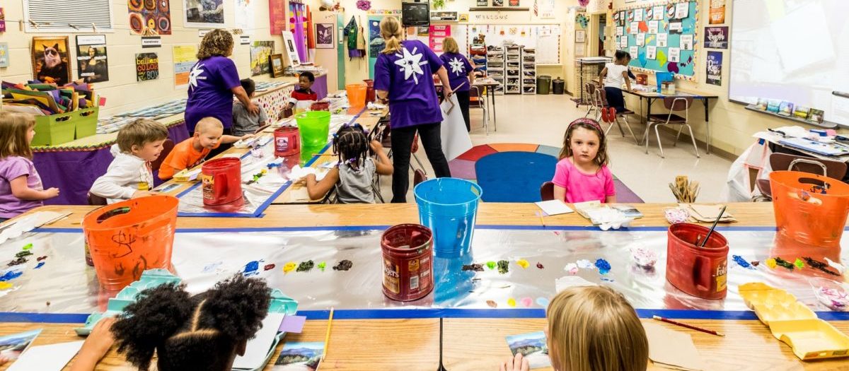 Photo of elementary-aged students and their teachers doing projects in an arts classroom.