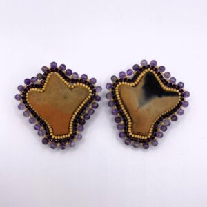 Earrings made from dark stone rimmed in tiny purple glass balls.