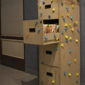 A beige filing cabinet stands with the second drawer ajar.
