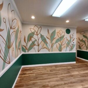 An indoor mural of leaves and outlines of flowers.