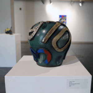 A deep turquoise clay pot with shapes in gray on it.