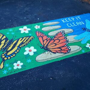 A storm drain mural of painted butterflies that reads, "Keep it clean."