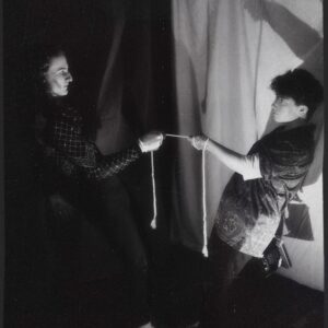 Black and white photo of two white people holding a section of rope