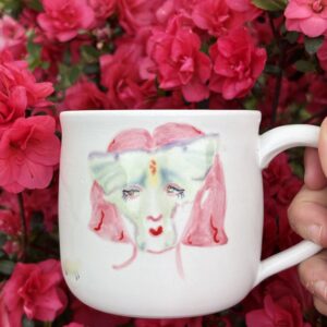 A hybrid moth/woman painted on a white ceramic mug.