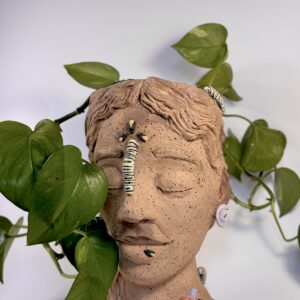 A clay bust of a woman's head with a caterpillar on the forehead